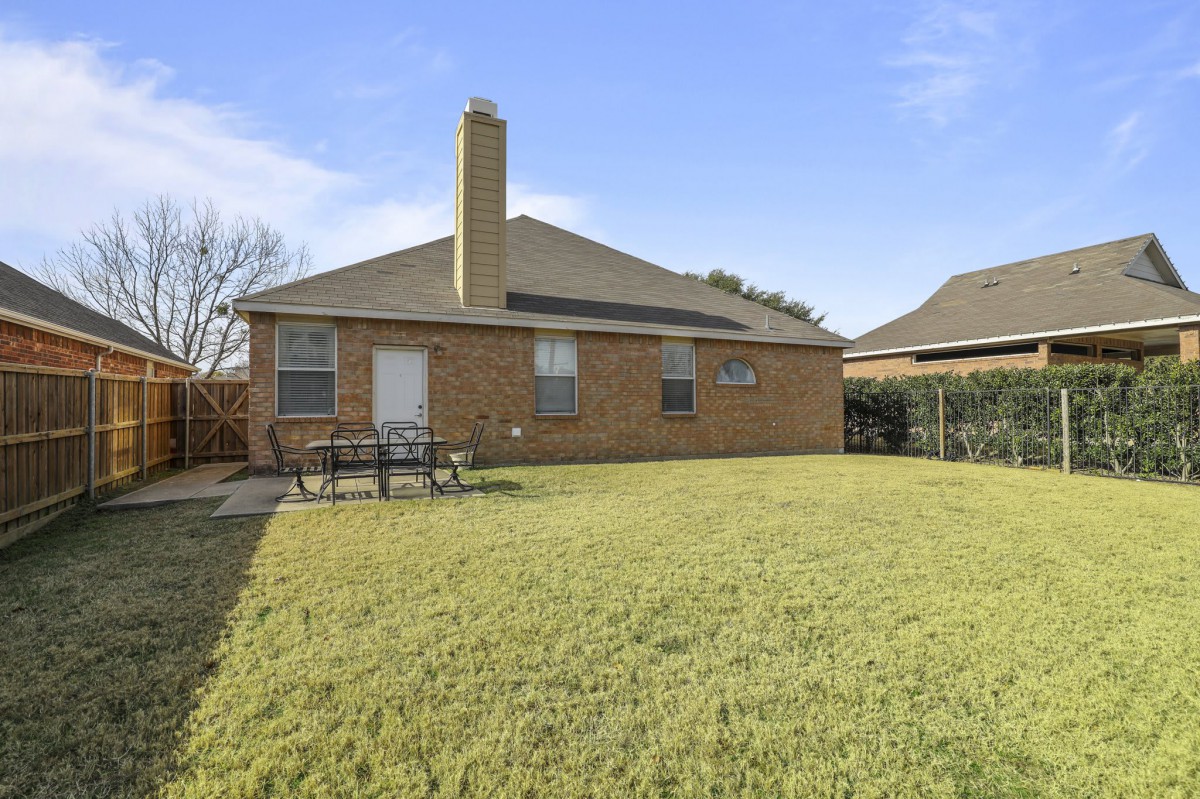 A suburban brick house with a spacious backyard and chimney.