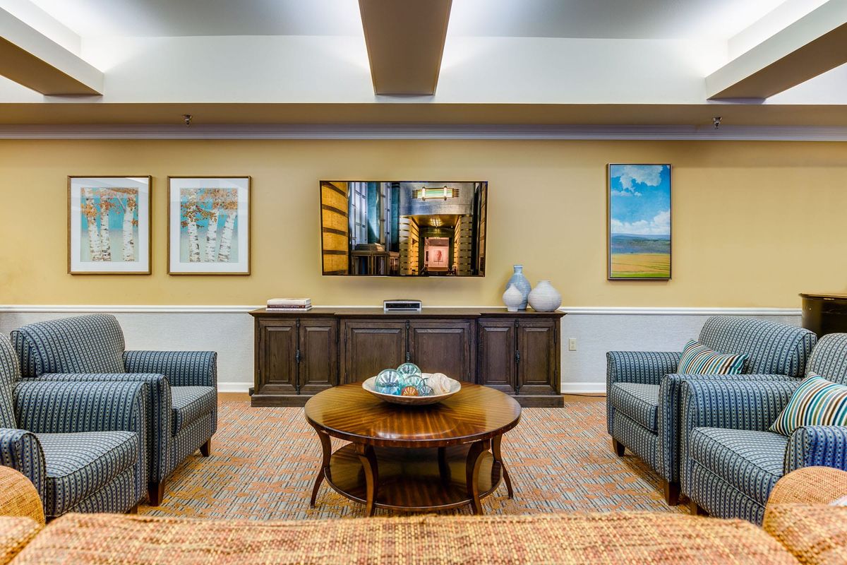 A cozy living room with comfortable seating, a wall-mounted TV, and decorative artwork.