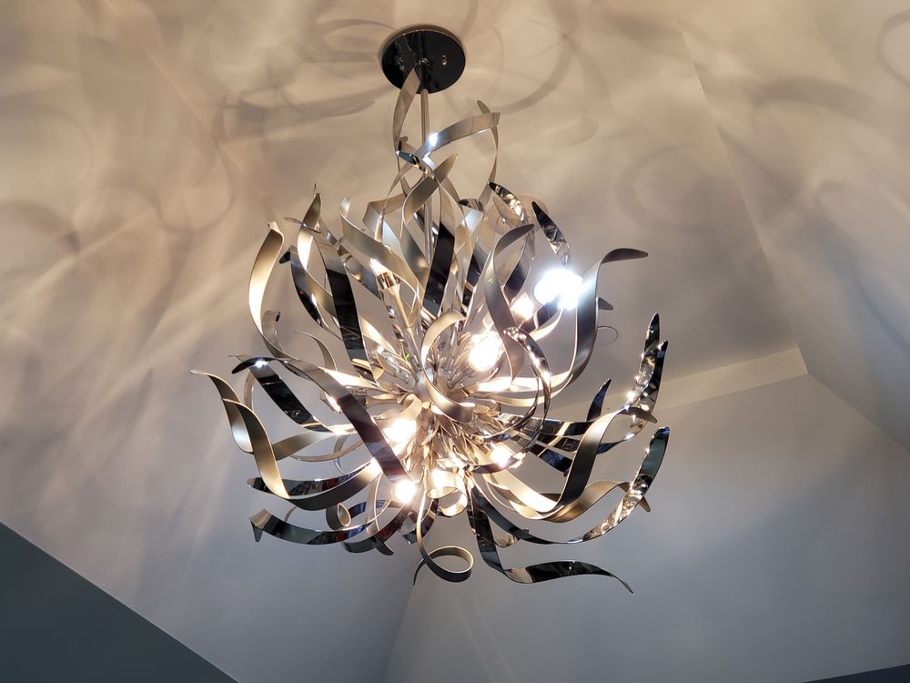 A modern metallic chandelier with a decorative design illuminates the room.