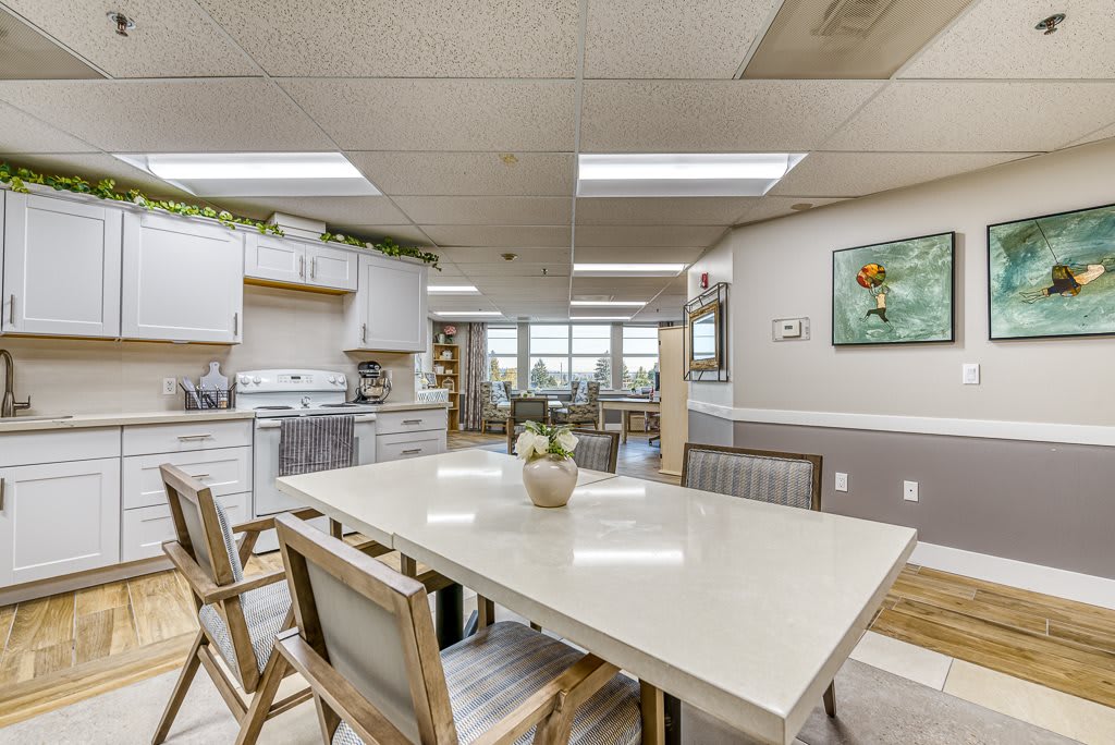 A modern kitchen and dining area with natural lighting and minimalist white decor.