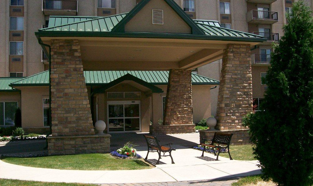 This image shows the entrance to a building with stone pillars and benches flanking a walkway.