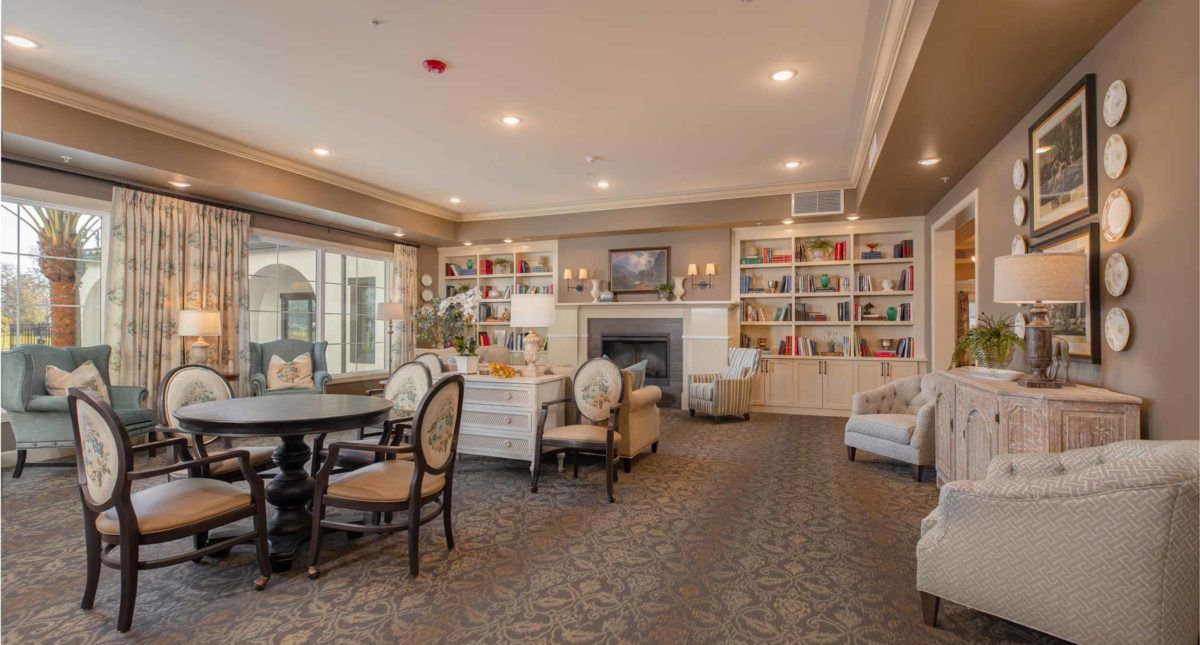 A cozy living room with elegant furniture, bookshelves, and a fireplace.