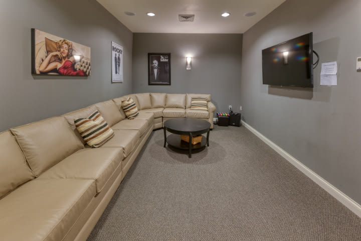 A cozy home theater with a large sectional sofa and a wall-mounted TV.