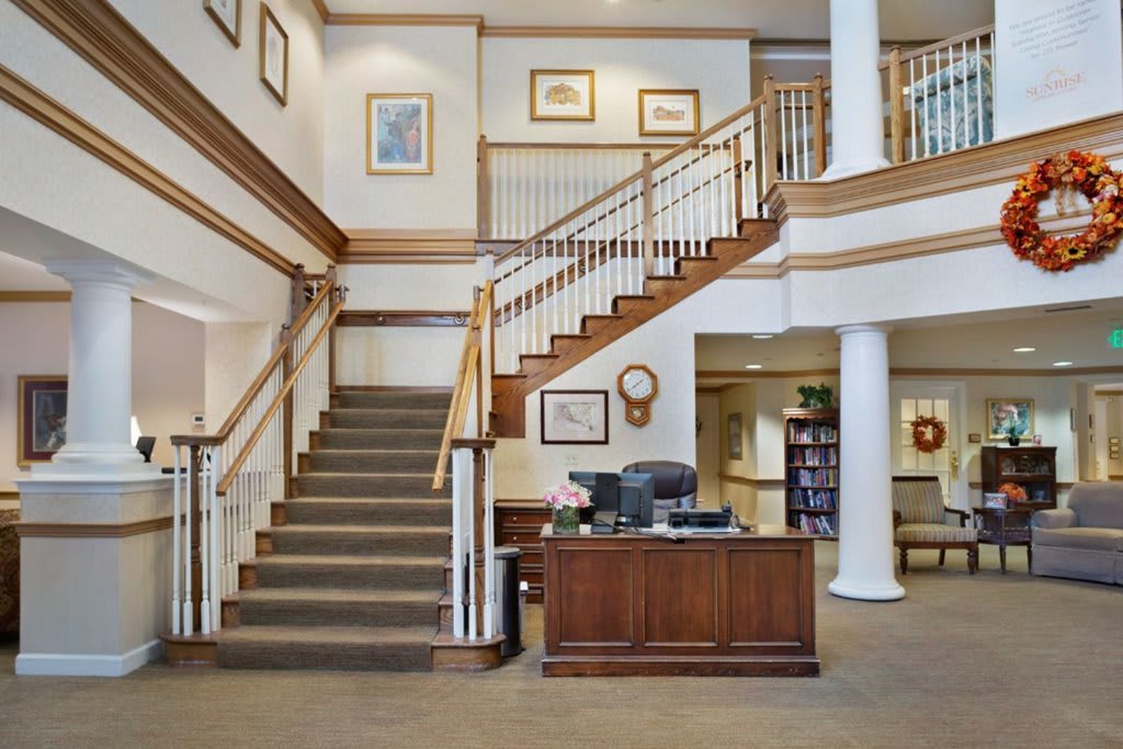 A welcoming lobby with a reception desk and staircase, featuring elegant wood accents and artwork on the walls.
