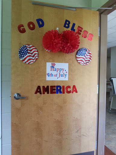 A patriotic door decoration celebrating July 4th with American flags and festive colors.