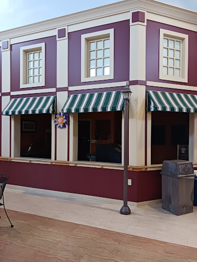 A view of a modern building exterior featuring large windows with green and white striped awnings.
