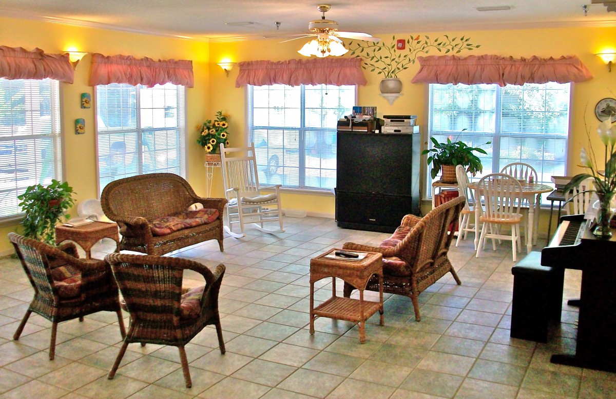 A cozy living room with wicker furniture, a television, and large windows letting in natural light.