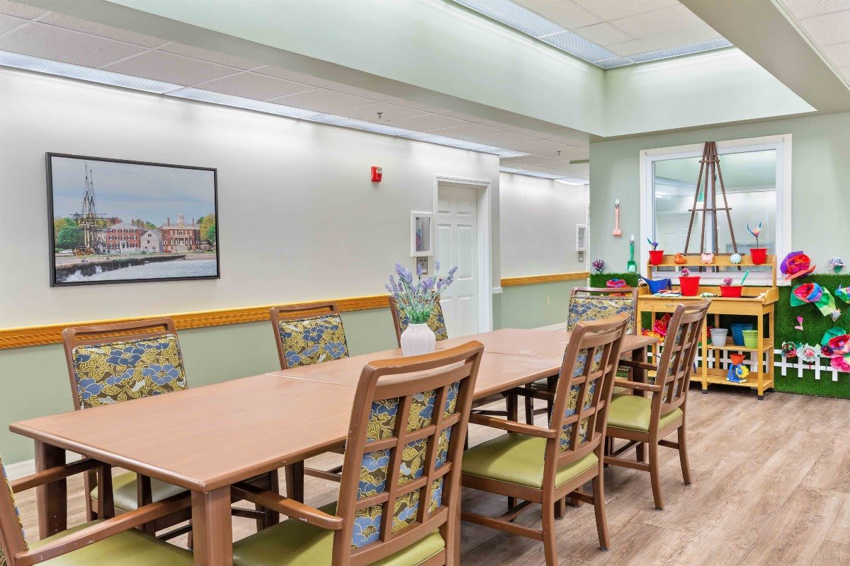 A spacious and well-lit dining area with a long table and multiple chairs, featuring modern decor.