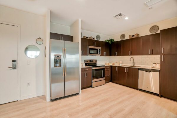 A modern kitchen with stainless steel appliances and wood flooring.