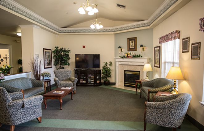 A cozy living room with a television and a fireplace, featuring comfortable seating and elegant decor.