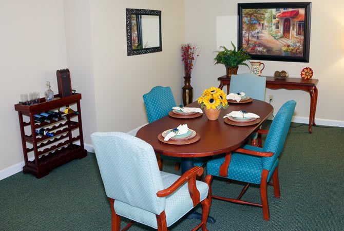 A cozy dining room with a wooden table set for four, featuring light blue chairs and home decor accents.