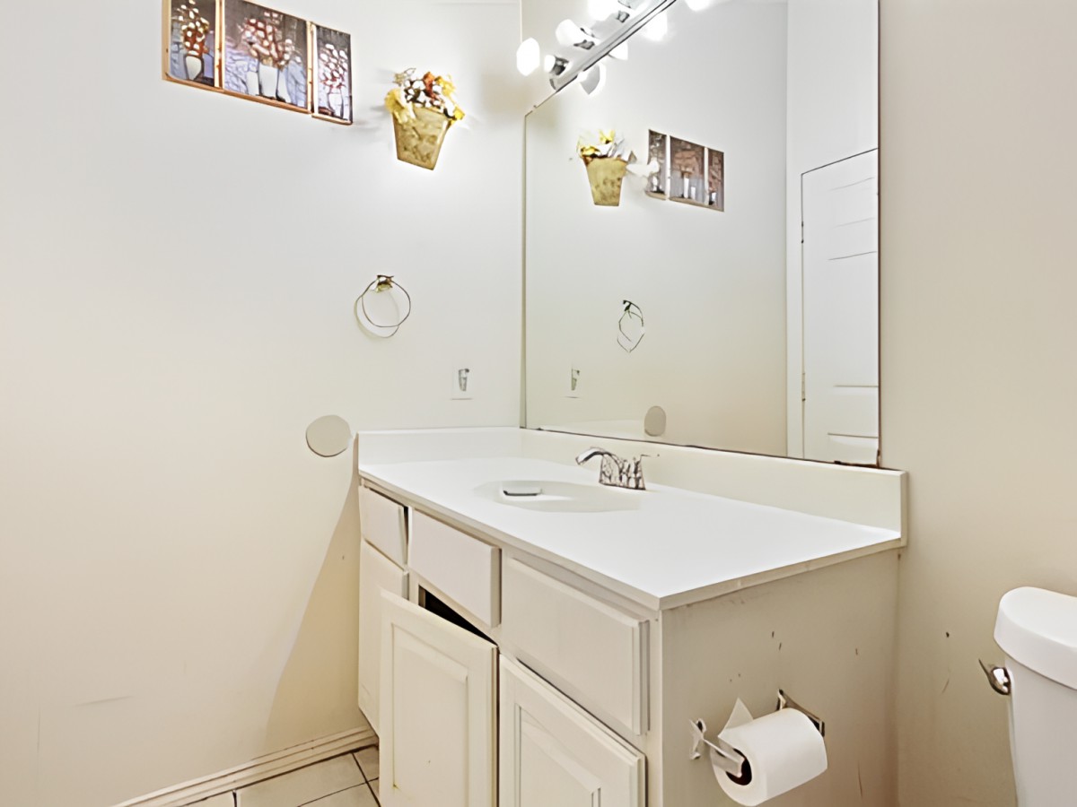 A clean and bright bathroom with a single sink, mirror, and decorative elements.