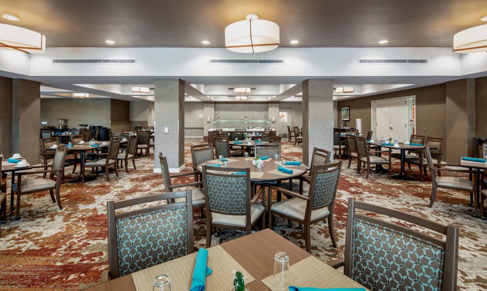 A spacious dining area with neatly arranged tables and chairs, featuring decorative napkins.