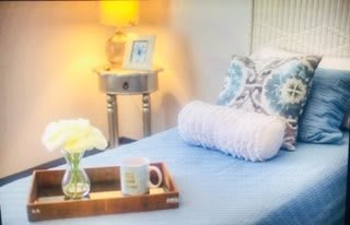 A cozy bedroom setup with a neatly made bed, decorative pillows, and a side table lamp.