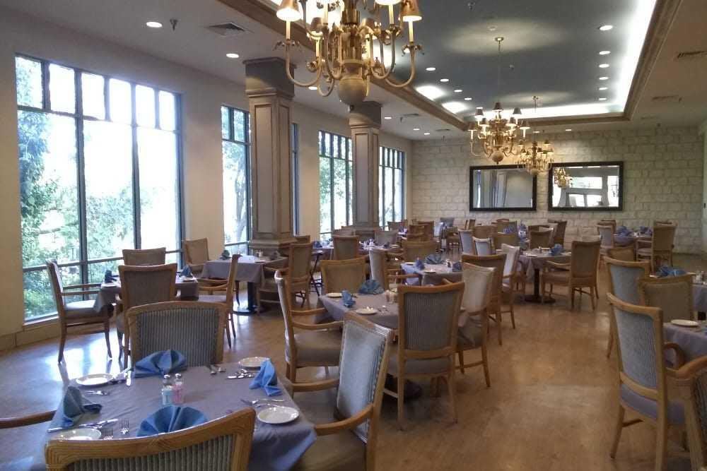 An elegant dining area with empty tables and chandeliers.