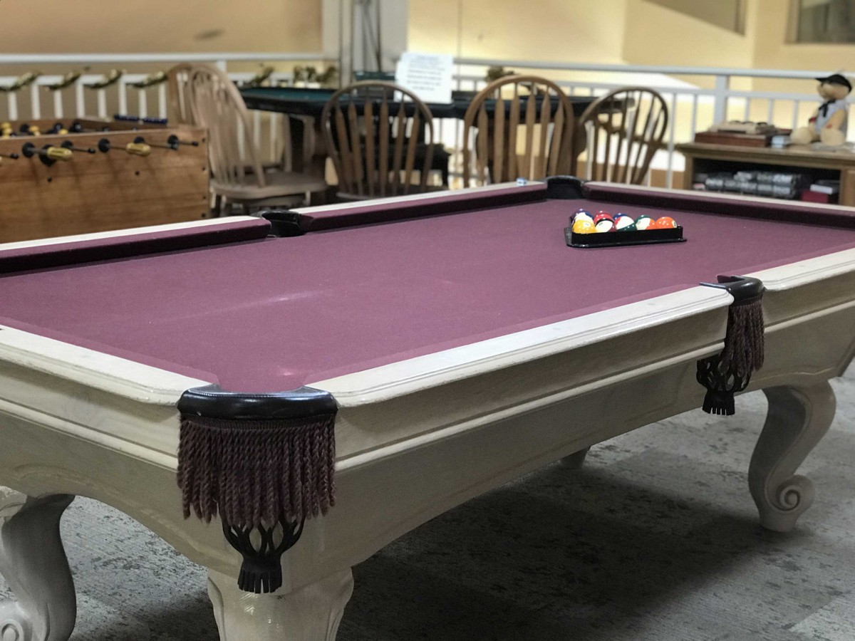 A pool table with a purple felt surface in an indoor setting.