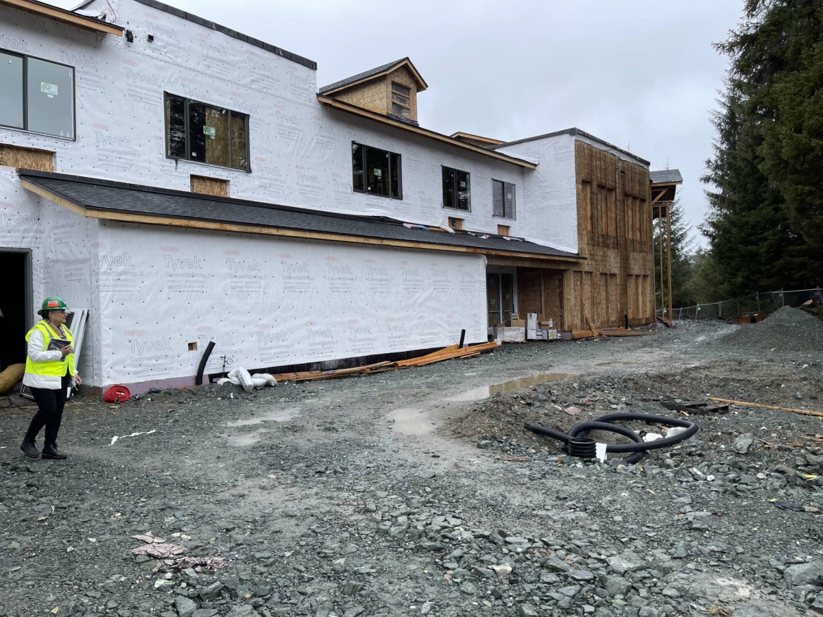 An unfinished house at a construction site with visible framework and building materials.