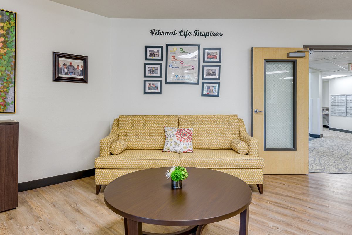 A cozy living room with a yellow sofa, wall art, and a round coffee table.