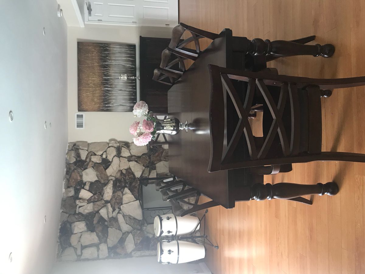 A cozy dining room with a dark wooden table, surrounded by chairs, and a stone accent wall.