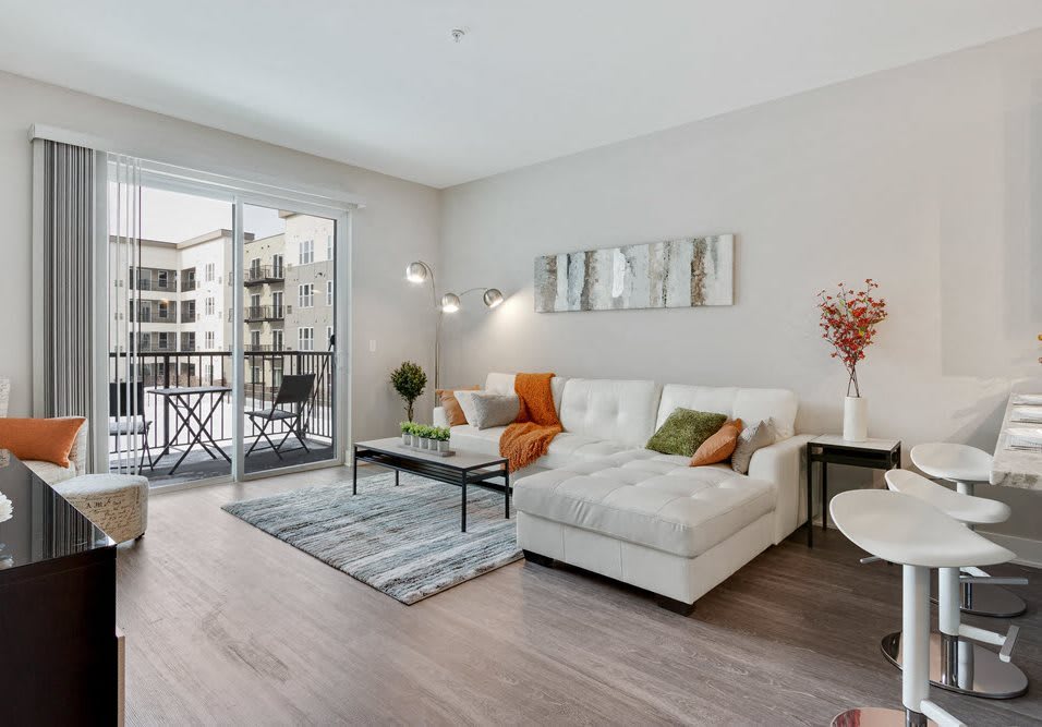 A modern living room with a comfortable sofa, stylish decor, and access to a balcony.