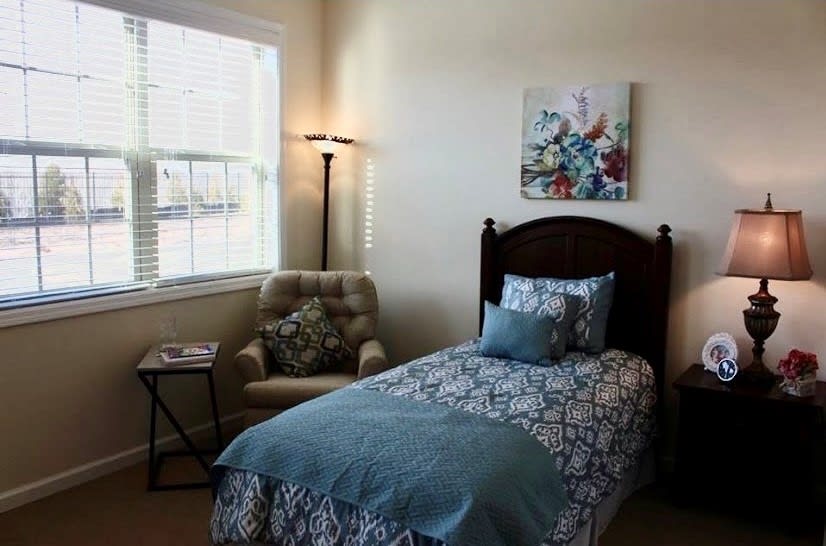 A cozy bedroom with a single bed and an armchair by the window.