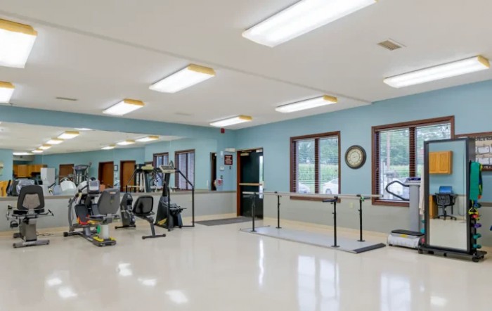 A spacious rehabilitation gym equipped with exercise machines and parallel bars.