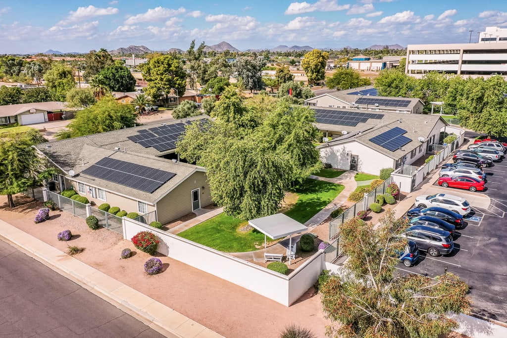 An aerial view of a residential area showcasing homes equipped with solar panels and surrounded by greenery.