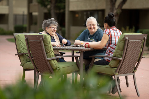 Three people enjoying a sunny day outdoors, engaged in a friendly conversation.