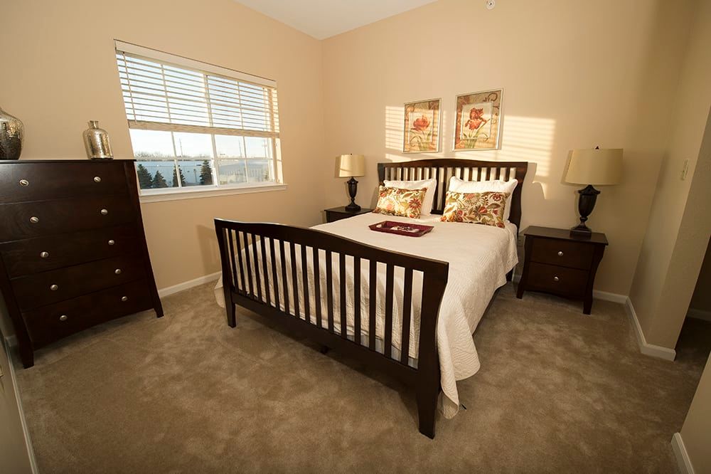 A cozy bedroom with a wooden bed frame, side tables, and decorative elements.