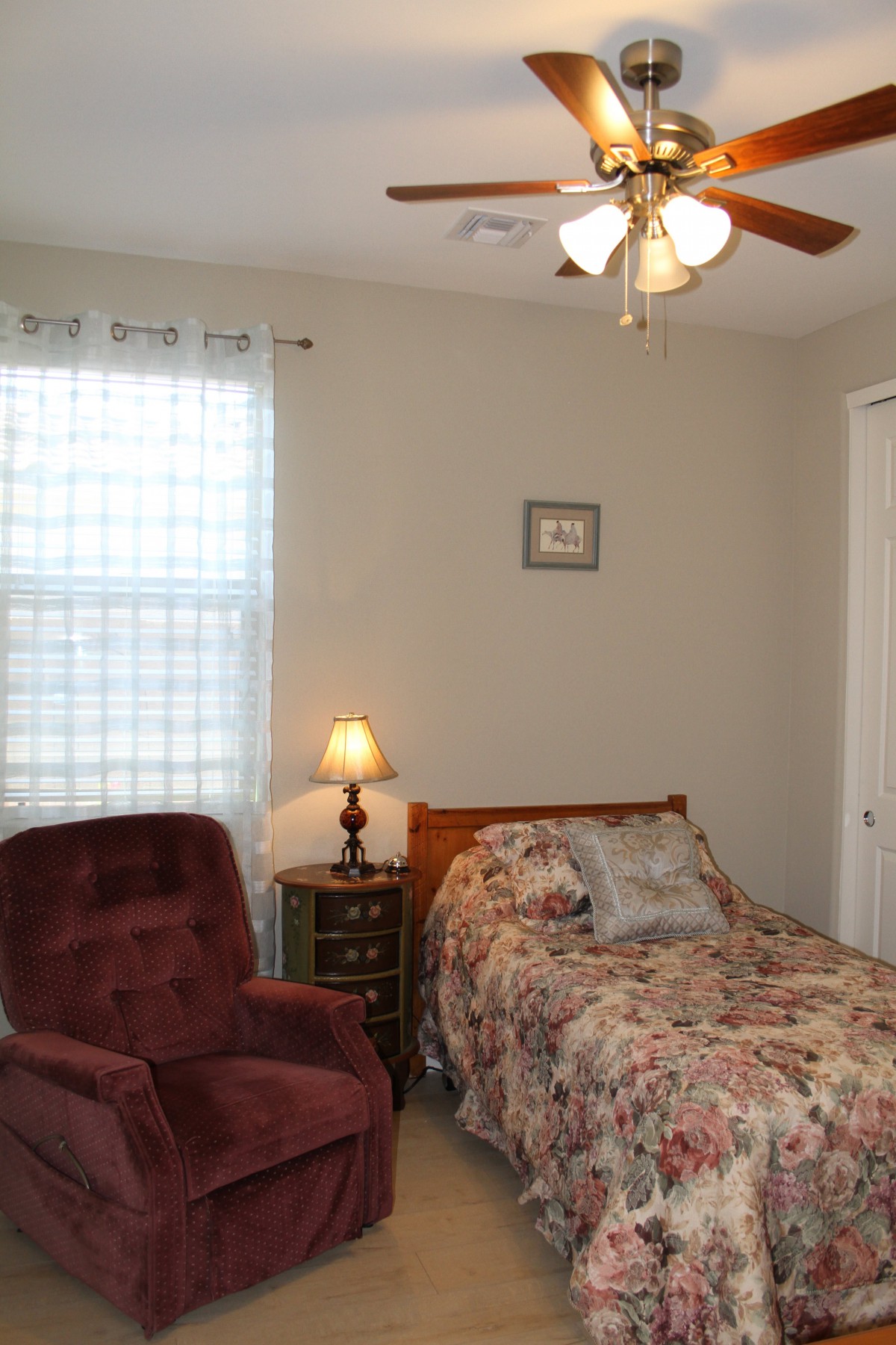A cozy bedroom with a single bed, an armchair, and a bedside lamp.