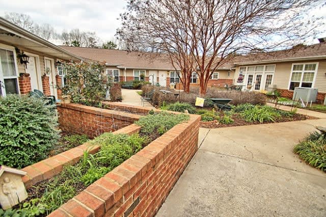 A peaceful courtyard with brick walls, landscaping, and walkways.