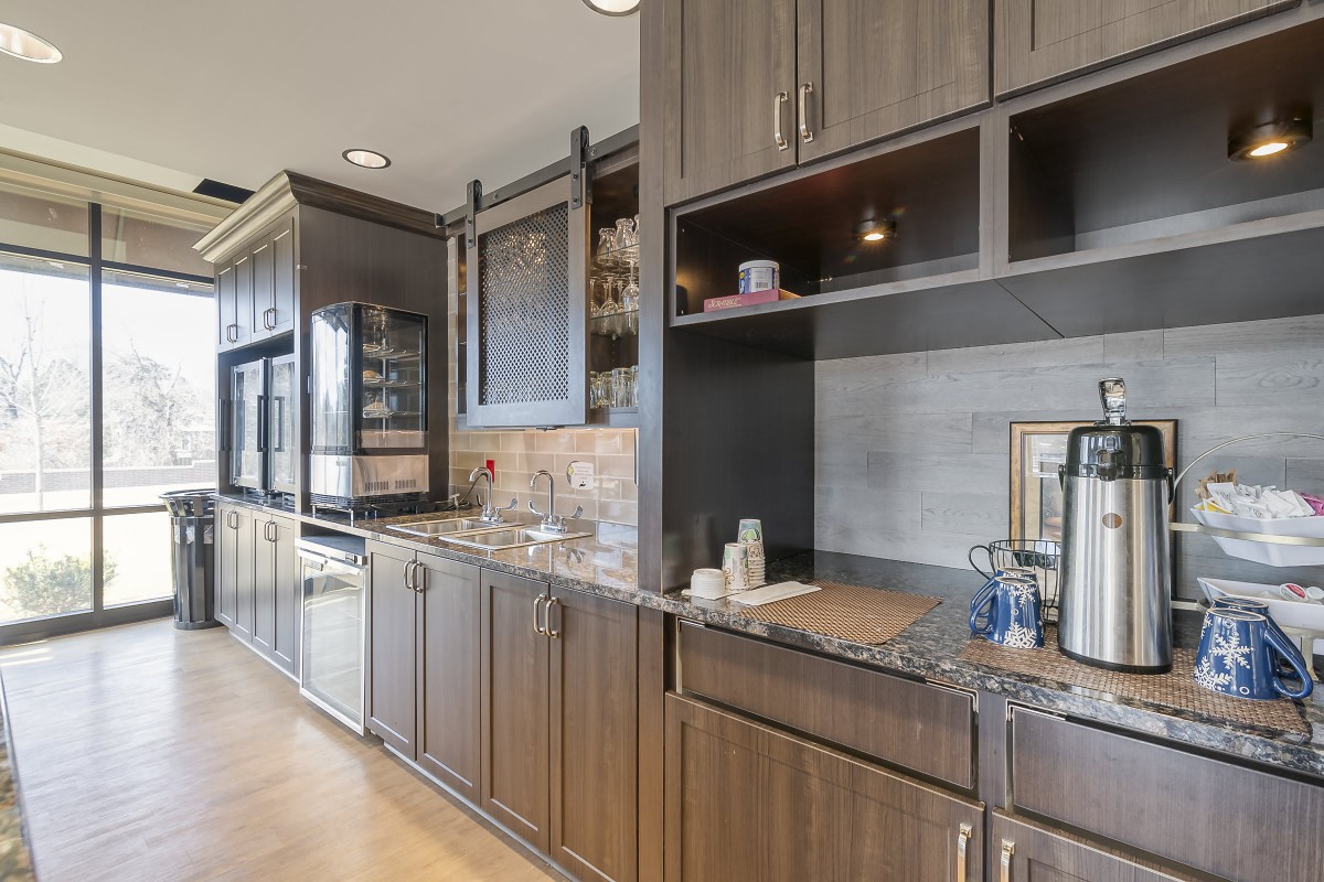A modern kitchen interior featuring dark wooden cabinets and a sleek countertop.