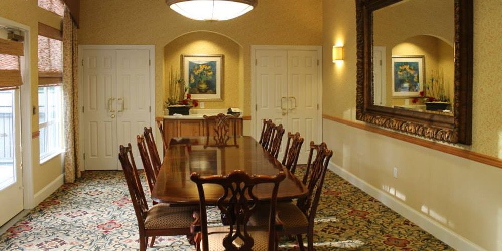 Elegant dining room with a long table and wooden chairs, adorned with artwork and a warm lighting ambiance.