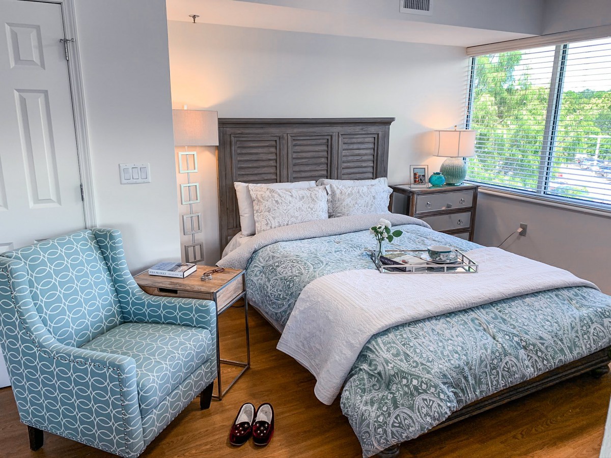 A cozy bedroom with a neatly made bed, decorative pillows, and a bedside table with lamps.