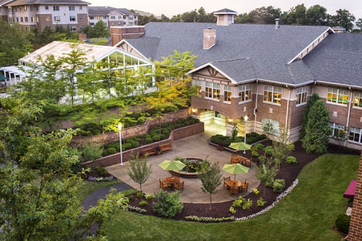 A beautifully landscaped outdoor space featuring a circular seating area surrounded by lush greenery and a modern building in the background.