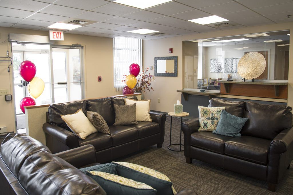 A cozy waiting room with leather sofas and decorative cushions, featuring a welcoming reception area.