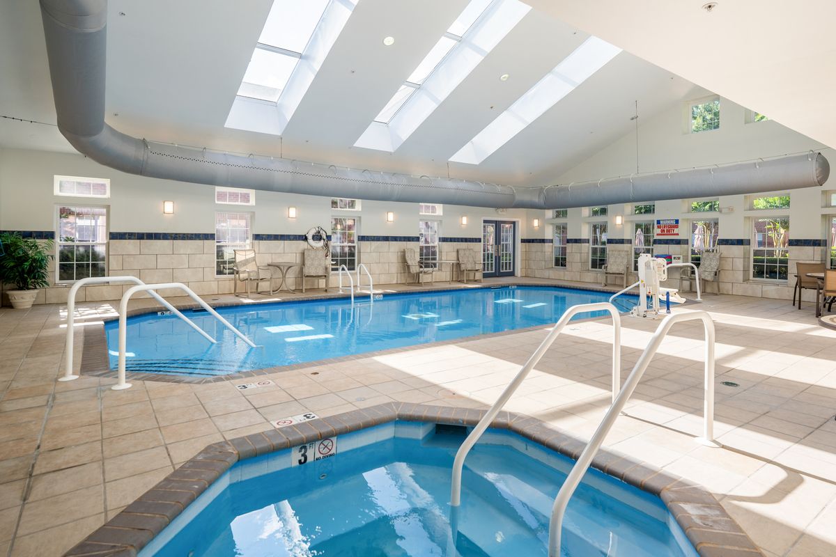 An inviting indoor swimming pool and hot tub area, illuminated by natural light from skylights above.