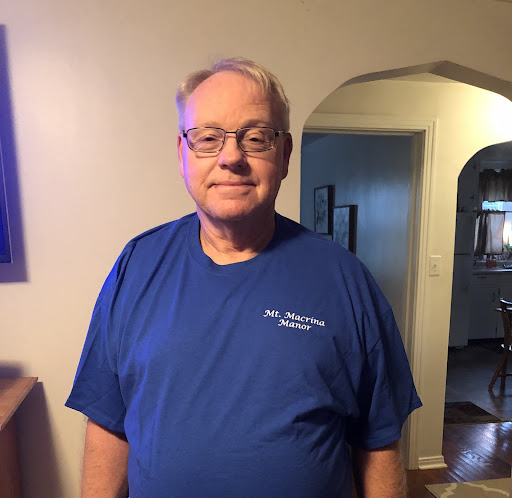 A man in a blue shirt poses for a photo indoors.