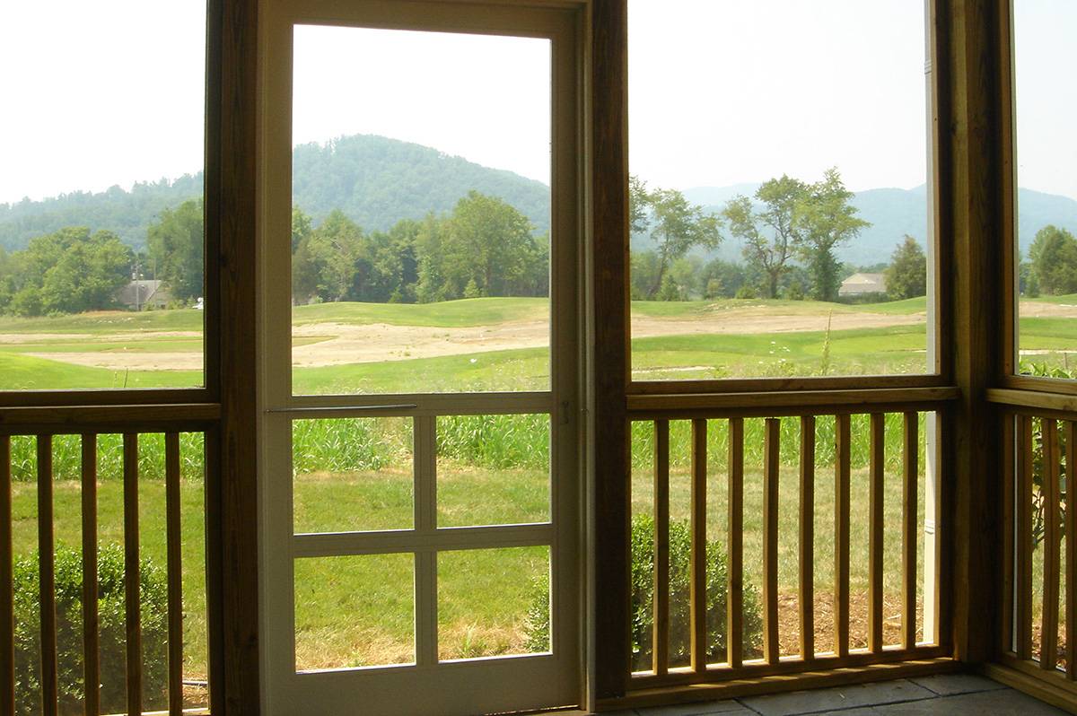 A scenic view of the outdoors through a porch doorway featuring mountains and greenery.