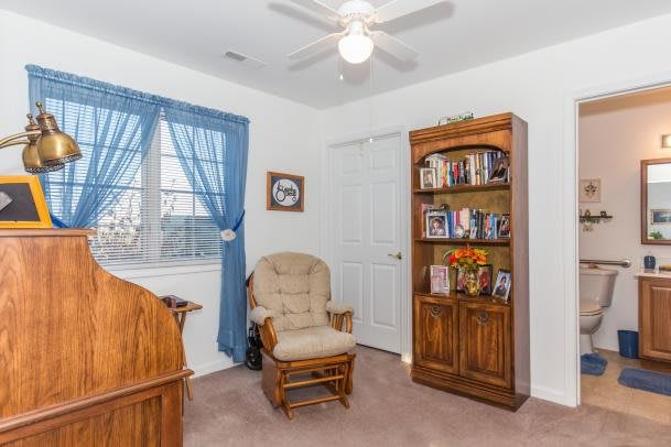 A cozy room with a bookshelf and a rocking chair next to a window.