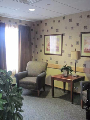 A cozy living room setting featuring comfortable chairs, a small table with a plant, and decorative wall art.