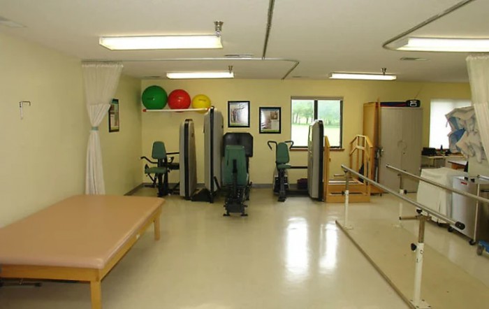 A well-equipped physical therapy room with exercise machines and therapy tables.