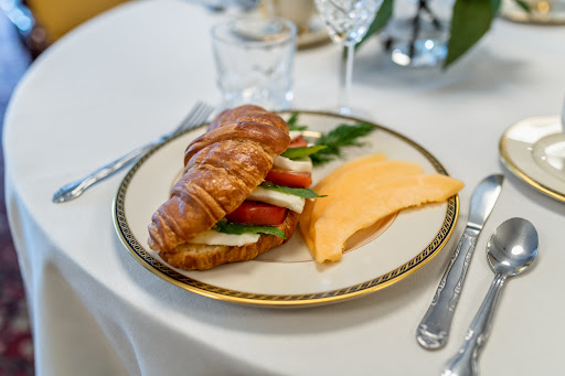 A delicious breakfast featuring a croissant filled with fresh vegetables and a side of cheese.