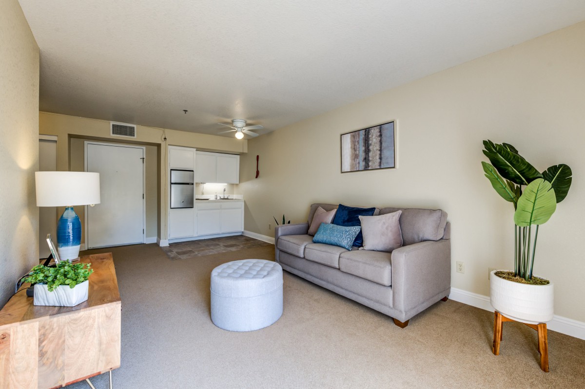 A cozy living room with a sofa, pouf, and open layout.