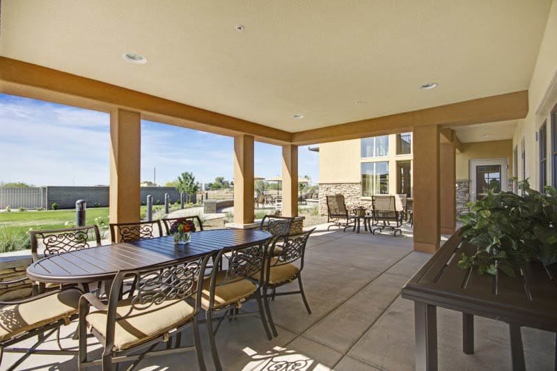 A spacious patio with a dining table and chairs, surrounded by open views on a sunny day.