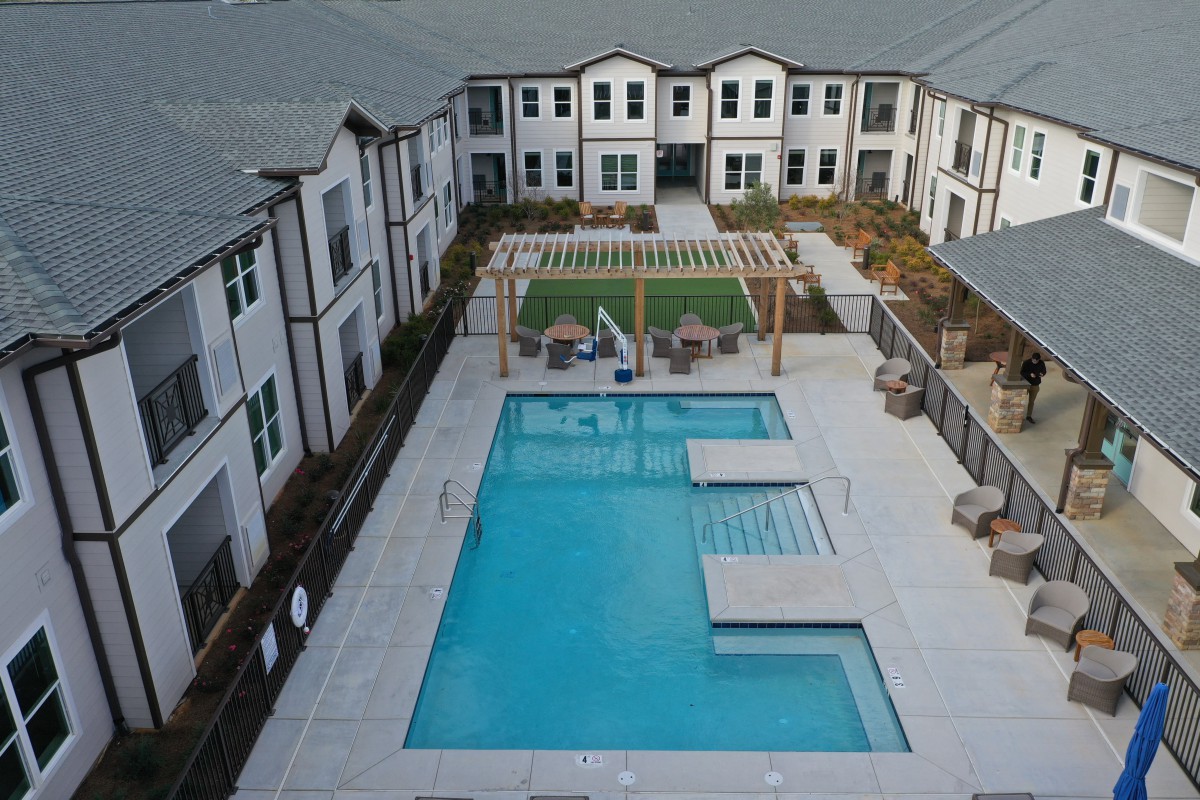 Modern apartment complex with a swimming pool and courtyard area.