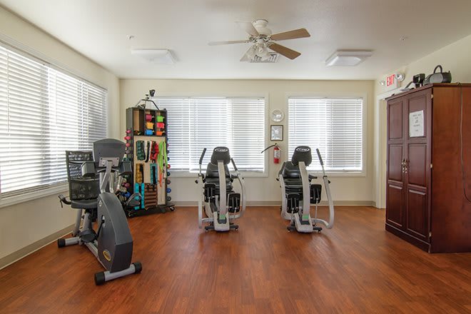 A well-lit gym room with exercise equipment and weights.