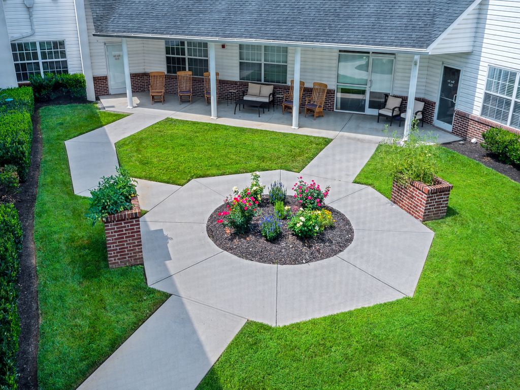 A well-maintained garden with a central flower bed surrounded by pathways and outdoor seating.