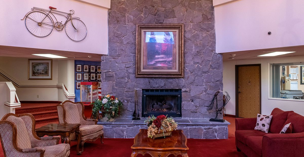 A cozy living room with a stone fireplace and artwork above, surrounded by elegant furniture and decor.