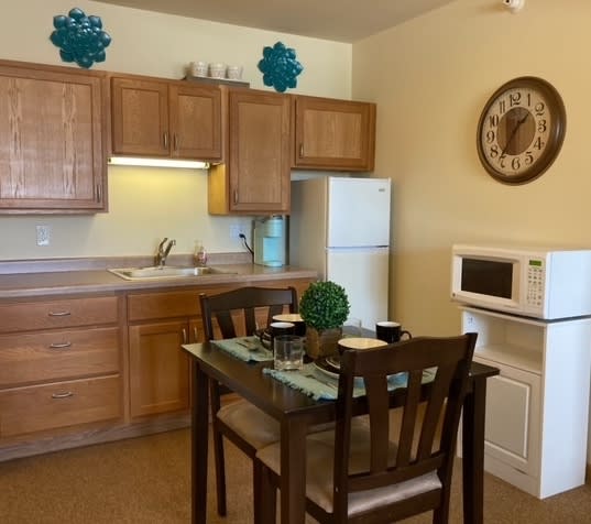 A cozy kitchen and dining area with wooden cabinets, a microwave, and a small dining table set.
